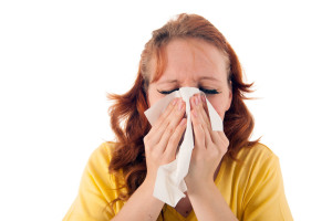 Red haired woman blowing nose