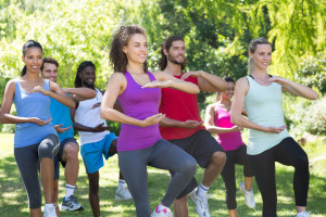 Fitness group doing tai chi in park on a sunny day