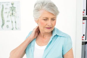 Senior woman suffering from neck pain with eyes closed in the medical office